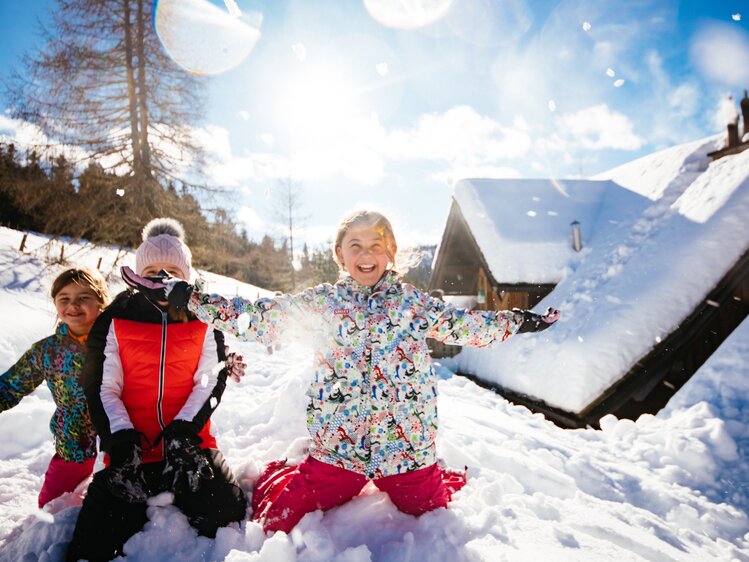 Kinder im Schnee | © Urlaub am Bauernhof Kärnten / Daniel Gollner Fröhliche Kinder in bunten Winterjacken und Hosen spielen ausgelassen im tiefen Schnee vor einer verschneiten Berglandschaft, die Arme ausgebreitet vor Freude. | © Urlaub am Bauernhof Kärnten / Daniel Gollner