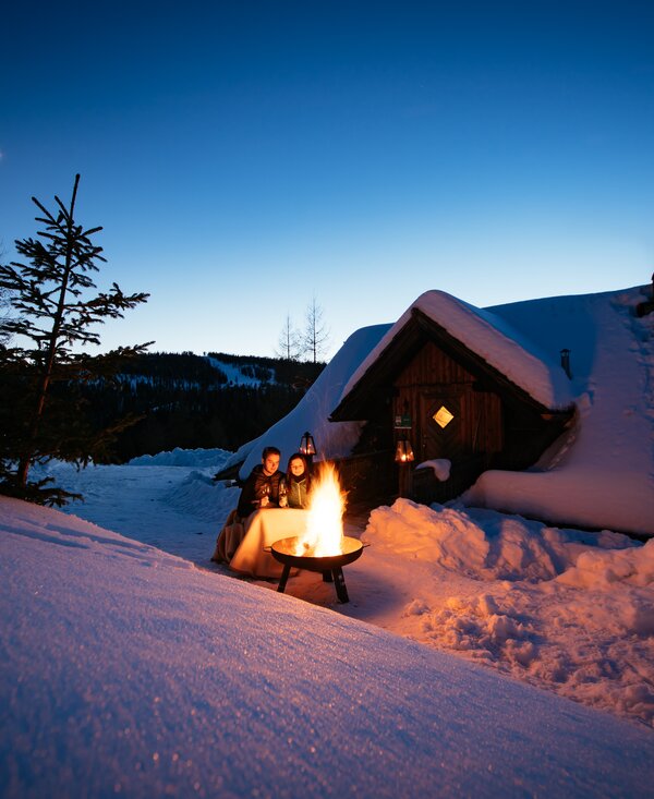 Lagerfeuerromantik auf der Almhütte | © Urlaub am Bauernhof Kärnten / Daniel Gollner Zwei Personen sitzen vor Lagerfeuer am Abend auf der Anderlehütte in Kärnten | © Urlaub am Bauernhof Kärnten / Daniel Gollner