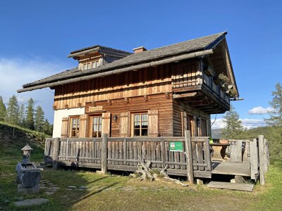 Mechtenhütte | © Urlaub am Bauernhof Kärnten / Jasmin Kreulitsch Traditionelles bayerisches Bergbauernhaus mit Holzbalkonen, Schindeldach und eingezäunter Terrasse in idyllischer Waldlandschaft. | © Urlaub am Bauernhof Kärnten / Jasmin Kreulitsch