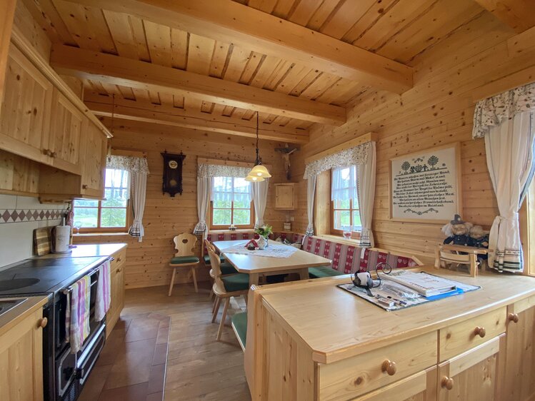 Gemütliches Holzinterieur mit traditioneller Einrichtung, Küchenzeile, Esstisch und Sitzgelegenheiten. Helle Beleuchtung und Dekoration schaffen eine heimelige Atmosphäre. | © Urlaub am Bauernhof Kärnten / Jasmin Kreulitsch