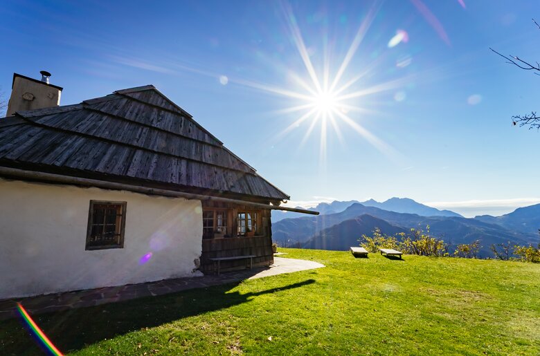Kleine Hütte mit Holzdach auf einer grünen Wiese, umgeben von Bergen und strahlendem Sonnenlicht. | © Urlaub am Bauernhof Kärnten/ Daniel Gollner