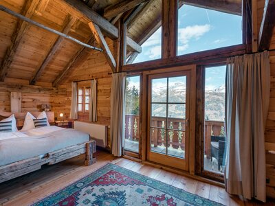 Geräumiges Holzchalet mit hohen Decken, großen Fenstern und Balkon mit Blick auf Berge. Gemütliche Einrichtung mit dekorativen Kissen, Teppich und rustikalen Möbeln. Einladende Atmosphäre für einen Entspannungsurlaub in den Bergen. | © Günter Standl 