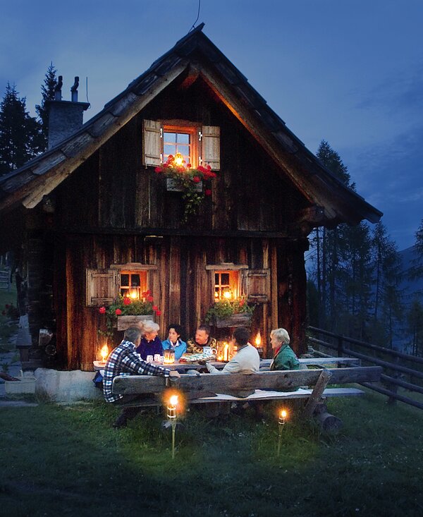 Herbstlicher Abend vor der Almhütte in Kärnten | © Urlaub am Bauernhof Kärnten/ Ernst P. Prokop Gruppe sitzt in gemeinsamer Runde vor einer Almhütte und genießt den herbstlichen Abend | © Urlaub am Bauernhof Kärnten/ Ernst P. Prokop