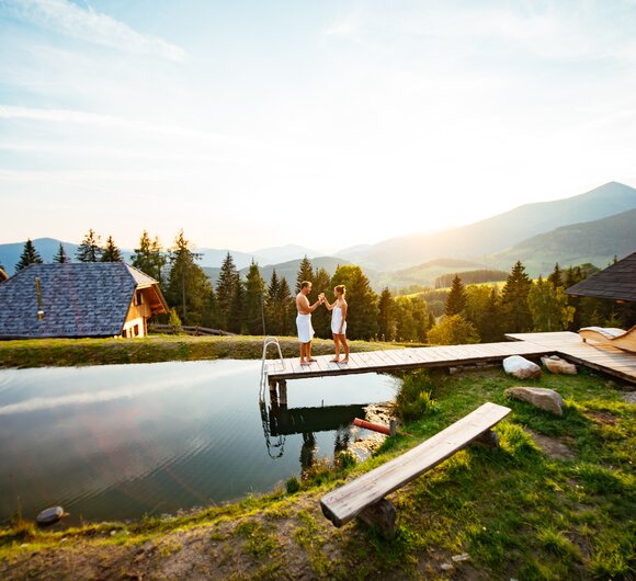 Paar steht am Badesteg im Sonnenuntergang und prostet sich zu | © Urlaub am Bauernhof Steiermark / Daniel Gollner 