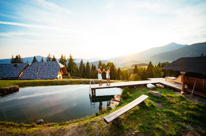 Paar steht am Badesteg im Sonnenuntergang und prostet sich zu | © Urlaub am Bauernhof Steiermark / Daniel Gollner 