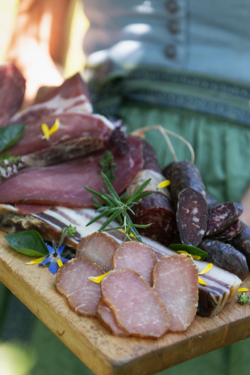Selbstgemachte Würstchen, Speck und Geselchtes am Holzbrettl präsentiert | © Carletto Photography / Urlaub am Bauernhof Kärnten