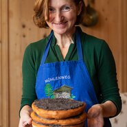 Helene Lugger vom Bauernhof im Wiesengrund serviert ihren Gästen fertige Stockplattln | © Carletto Photography / Urlaub am Bauernhof Kärnten