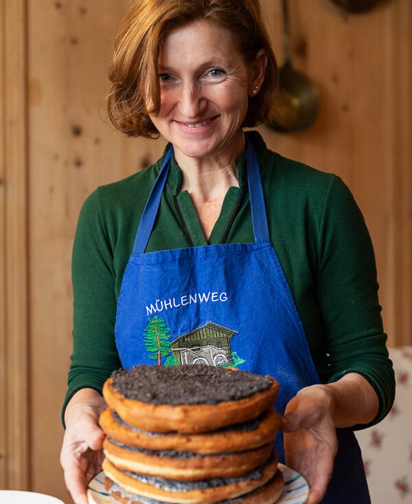 Helene Lugger vom Bauernhof im Wiesengrund serviert ihren Gästen fertige Stockplattln | © Carletto Photography / Urlaub am Bauernhof Kärnten