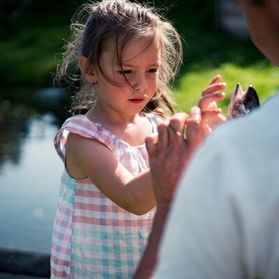 Mädchen greift frischen Fisch an | © Urlaub am Bauernhof Kärnten/ Daniel Gollner