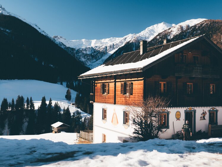 Bauernhaus in der verschneiten Landschaft mit Bergen im Hintergrund | © Urlaub am Bauernhof Kärnten / Daniel Gollner