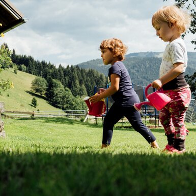 Kinder mit Gießkannen auf der Wiese | © Urlaub am Bauernhof Kärnten / Daniel Gollner