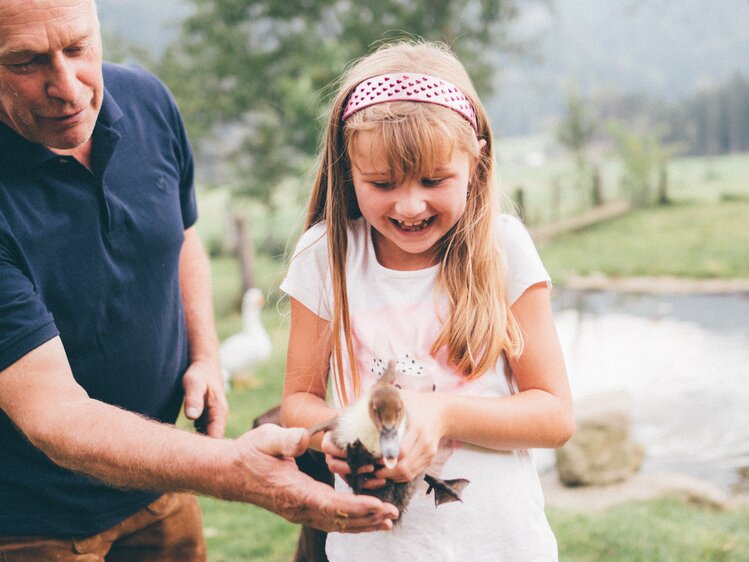 Mann und Mädchen hält Ente in der Hand | © Urlaub am Bauernhof Kärnten / Daniel Gollner