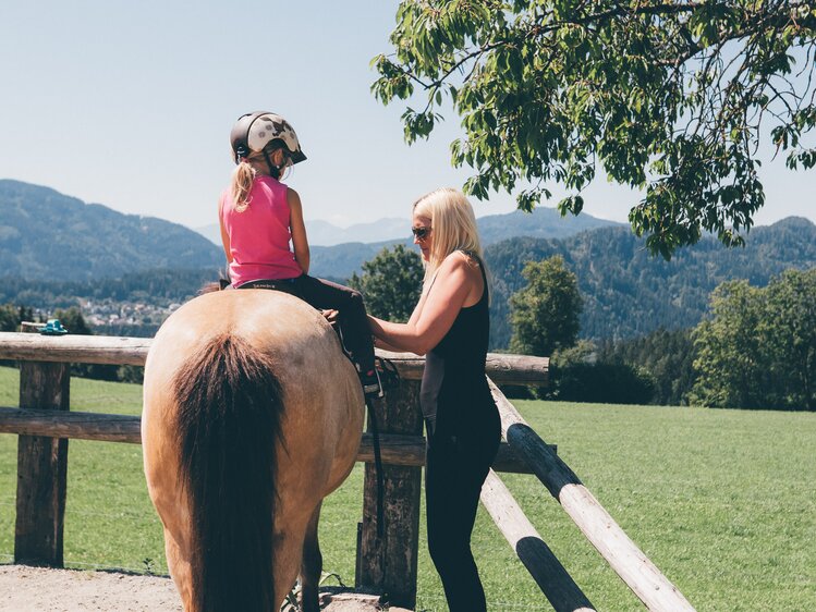 Mädchen sitzt auf dem Pferd und Frau steht daneben | © Urlaub am Bauernhof Kärnten / Daniel Gollner