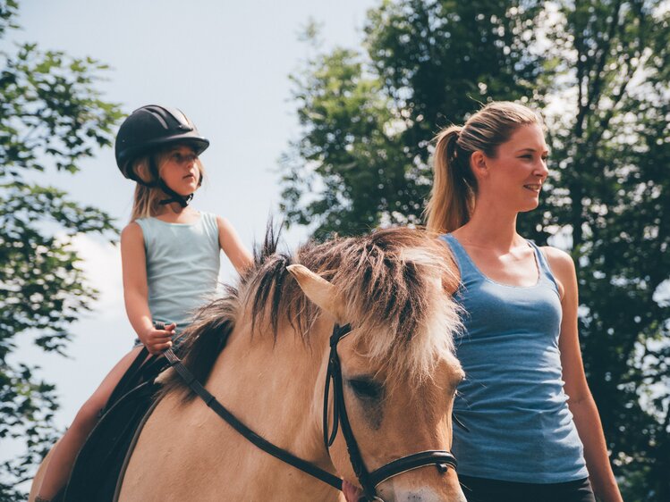 Frau führt Pferd und Kind reitet | © Urlaub am Bauernhof Kärnten / Daniel Gollner