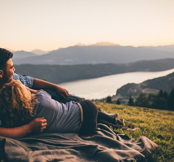 Paar liegt auf der Decke auf der Wiese und genießt den Ausblick | © Urlaub am Bauernhof Kärnten/ Daniel Gollner