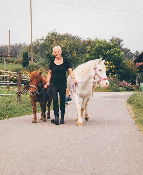 Frau mit den Pferden | © Urlaub am Bauernhof Kärnten/ Daniel Gollner Frau führt Pferde am Weg | © Urlaub am Bauernhof Kärnten/ Daniel Gollner