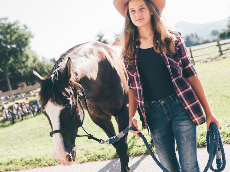 Frau führt das Pferd auf der Wiese | © Urlaub am Bauernhof Kärnten / Daniel Gollner