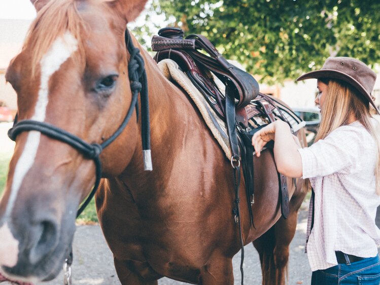 Frau sattelt das Pferd | © Urlaub am Bauernhof Kärnten / Daniel Gollner