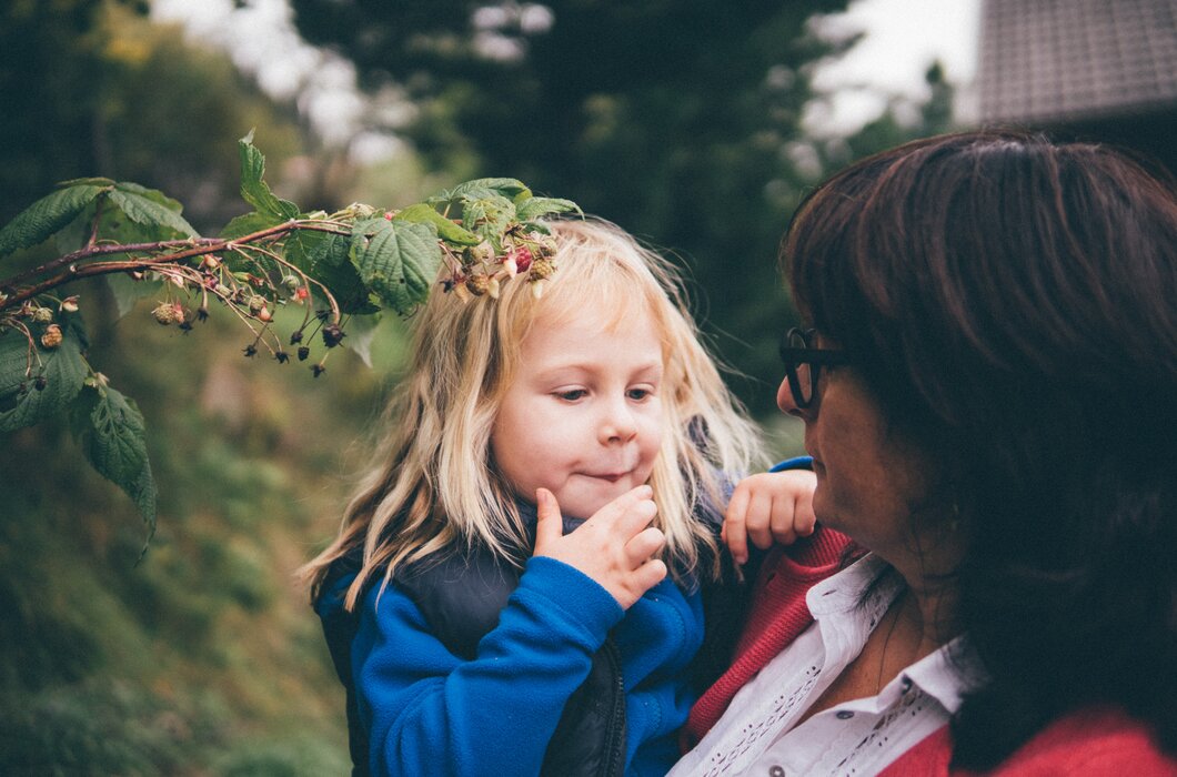 Frau hebt Mädchen | © Urlaub am Bauernhof Kärnten/ Daniel Gollner Frau hebt Mädchen vor dem Strauch | © Urlaub am Bauernhof Kärnten/ Daniel Gollner
