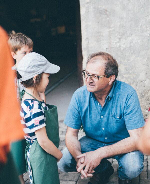 Bauer und Kinder | © Urlaub am Bauernhof Kärnten / Daniel Gollner Bauer hockt bei den Kindern | © Urlaub am Bauernhof Kärnten / Daniel Gollner