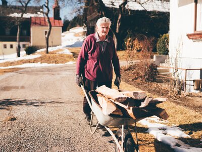 Bäuerin mit Holz | © Urlaub am Bauernhof Kärnten / Daniel Gollner Bäuerin fährt mit dem Holz in der Scheibtruhe | © Urlaub am Bauernhof Kärnten / Daniel Gollner