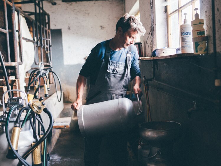 Bauer mit der Milchkanne im Stall | © Urlaub am Bauernhof Kärnten / Daniel Gollner