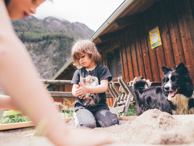 Kinder sitzen vor der Hütte mit dem Hund am Boden | © Urlaub am Bauernhof Kärnten / Daniel Gollner