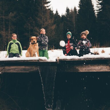 Kinder und Hund knien im Schnee | © Urlaub am Bauernhof Kärnten / Daniel Gollner