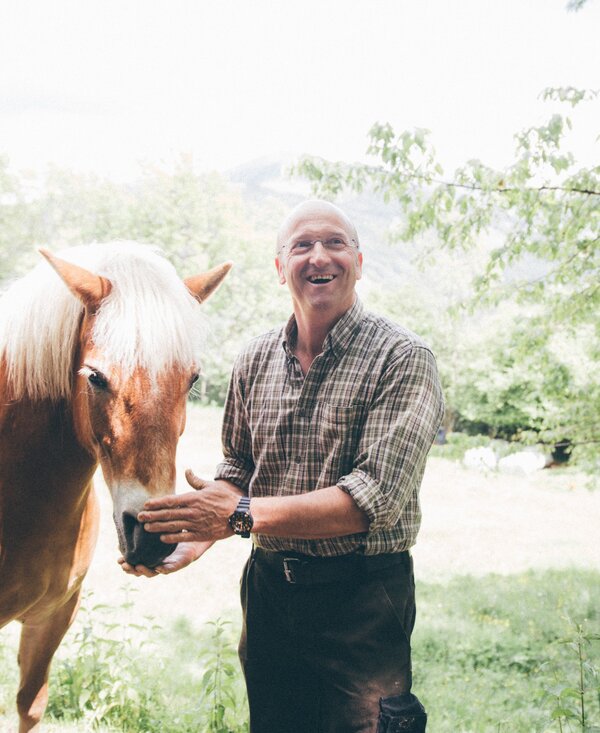 Mann steht bei Pferd und greift auf den Kopf des Pferdes | © Urlaub am Bauernhof Kärnten / Daniel Gollner