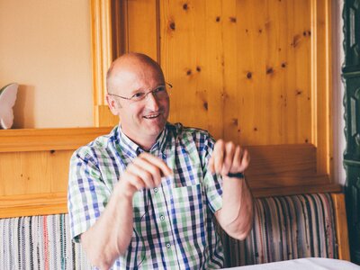 Mann sitzt bei Tisch | © Urlaub am Bauernhof Kärnten / Daniel Gollner Mann sitzt bei Tisch und erklärt etwas | © Urlaub am Bauernhof Kärnten / Daniel Gollner