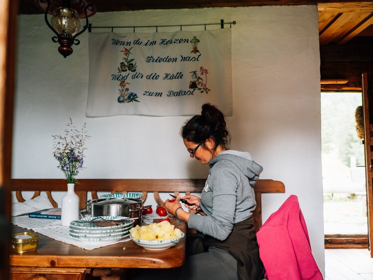 Frau sitzt am Tisch und bereitet das Essen vor | © Urlaub am Bauernhof Kärnten / Daniel Gollner