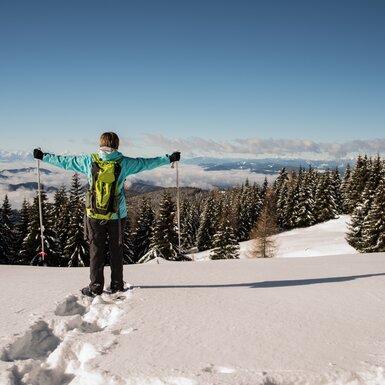 Schneeschuhwandern auf der Saualpe | © Tourismusregion Mittelkärnten Schneeschuhwanderin steht im Tiefschnee und hebt die Arme | © Tourismusregion Mittelkärnten