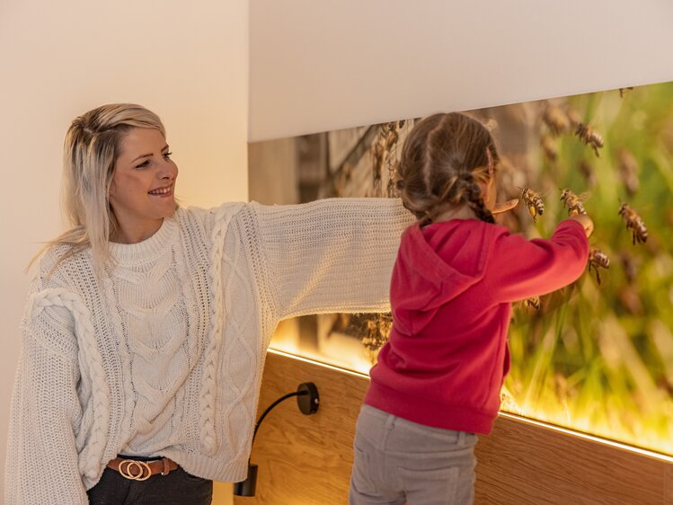 Die Frau und das Mädchen betrachten das Bild der Bienen im Schlafzimmer | © Urlaub am Bauernhof Kärnten/ Achim Mandler