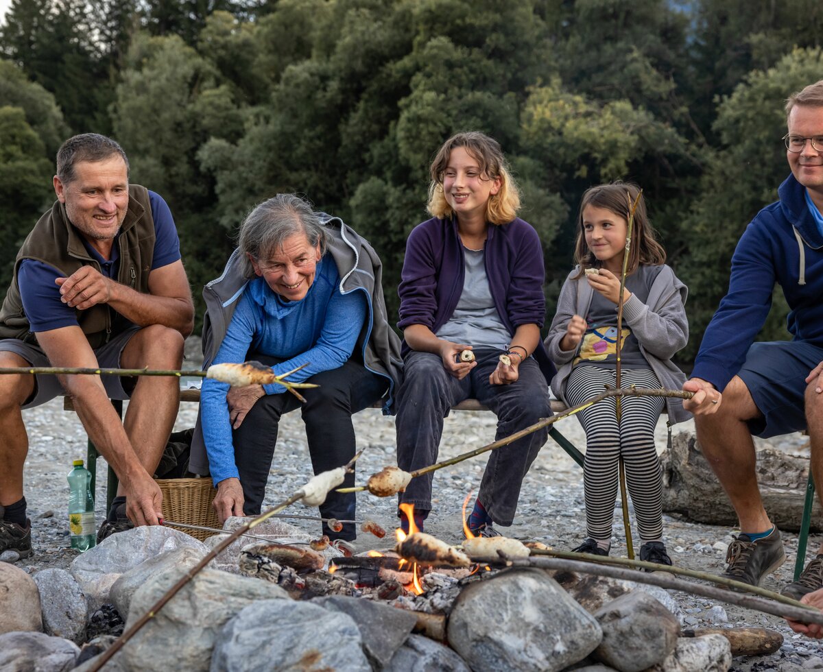 Familie grillt das Stockbrot am Lagerfeuer am Flussufer | © Landesverband Urlaub am Bauernhof Kärnten/ Achim Mandler
