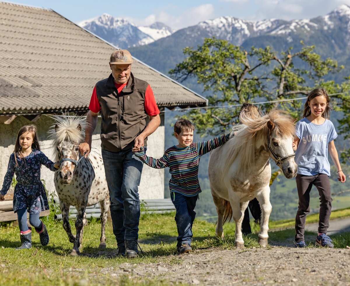 Bauer und Kinder mit den Ponys | © Landesverband Urlaub am Bauernhof Kärnten/ Achim Mandler Bauer und Kinder gehen mit den Ponys | © Landesverband Urlaub am Bauernhof Kärnten/ Achim Mandler