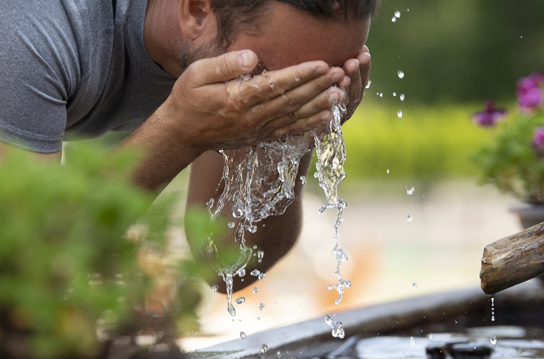 Mann erfrischt sich nach dem Wandern mit kühlem Wasser vom Brunnen | © Urlaub am Bauernhof Oberösterreich / Andreas Hofer
