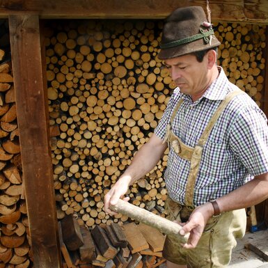 Bauer zeigt ein Stück Holz her | © Urlaub am Bauernhof Oberösterreich / Harald Puchegger