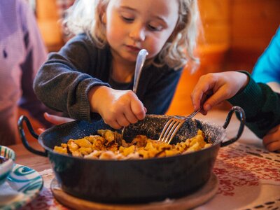 Mädchen isst aus einer Pfanne mit Kaiserschmarren | © Urlaub am Bauernhof Oberösterreich / Pascal Baronit
