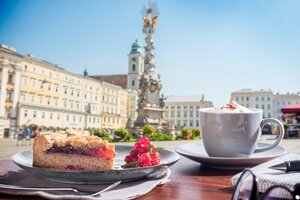 Ein Stück Linzer Torte und ein Cappuccino in einem Gastgarten mit Blick auf den Linzer Hauptplatz | © Linz Tourismus / ms Fotogroup