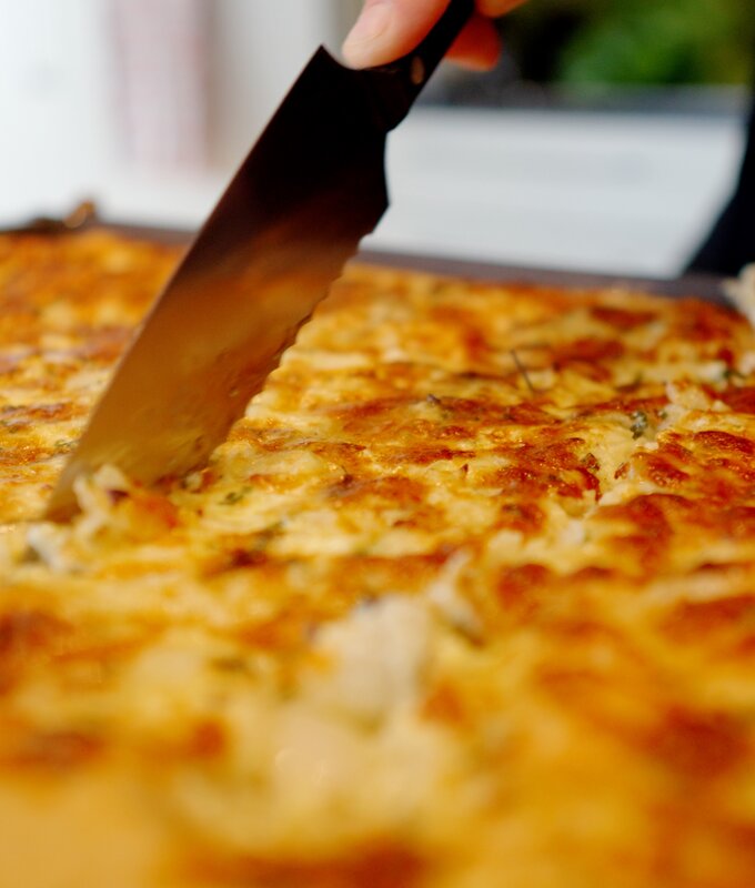 Eine leckere, goldbraune Tortilla mit geschmolzenem Käse, die gerade mit einem Messer zerteilt wird. | © Urlaub am Bauernhof / Daniel Gollner