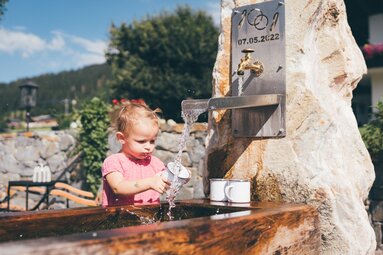Maedchen trinkt von Brunnen mit Tasse | © Urlaub am Bauernhof / Daniel Gollner
