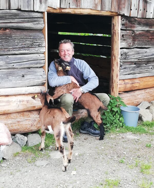 Ziegen mit Mann | © Urlaub am Bauernhof Österreich Mann umarmt Ziegen | © Urlaub am Bauernhof Österreich