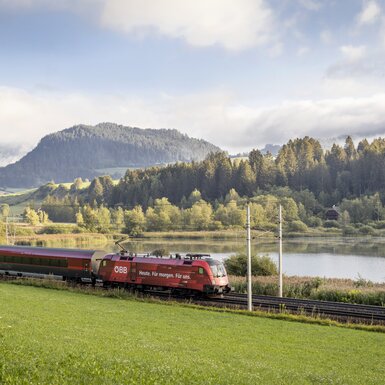 Bei der Anreise zur Ruhe kommen mit Blick auf Wälder und Flüsse | © ÖBB / Harald Eisenberger Zug fährt an einem Fluss entlang | © ÖBB / Harald Eisenberger