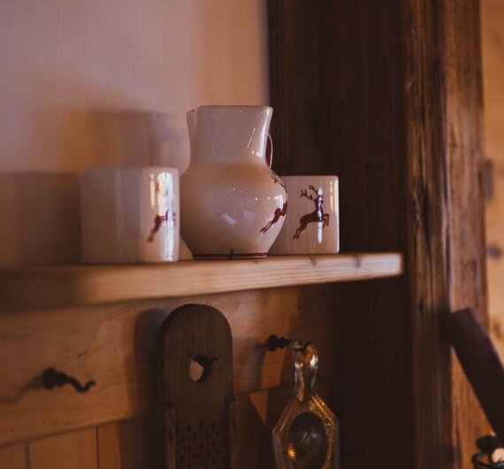 Vasen auf einem Regal | © Urlaub am Bauernhof / Pascal Baronit Holzregale mit Keramikvasen, Dekorationselementen und Werkzeugen an der Wand in einem gemütlichen, rustikalen Ambiente. | © Urlaub am Bauernhof / Pascal Baronit