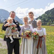 Familie Berger vor einem Blumenfeld und einer weißen Berglandschaft. | © Torbauer/Familie Berger