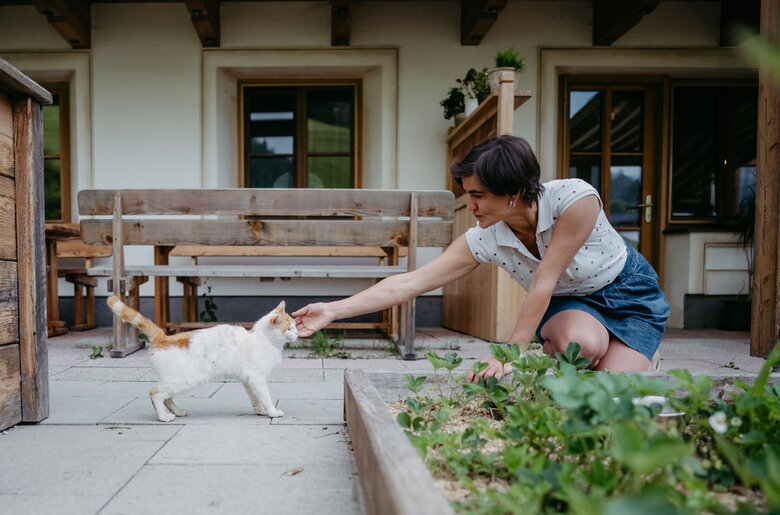 Baeuerin mit Katze im Garten | © Urlaub am Bauernhof / Nadia Jabil