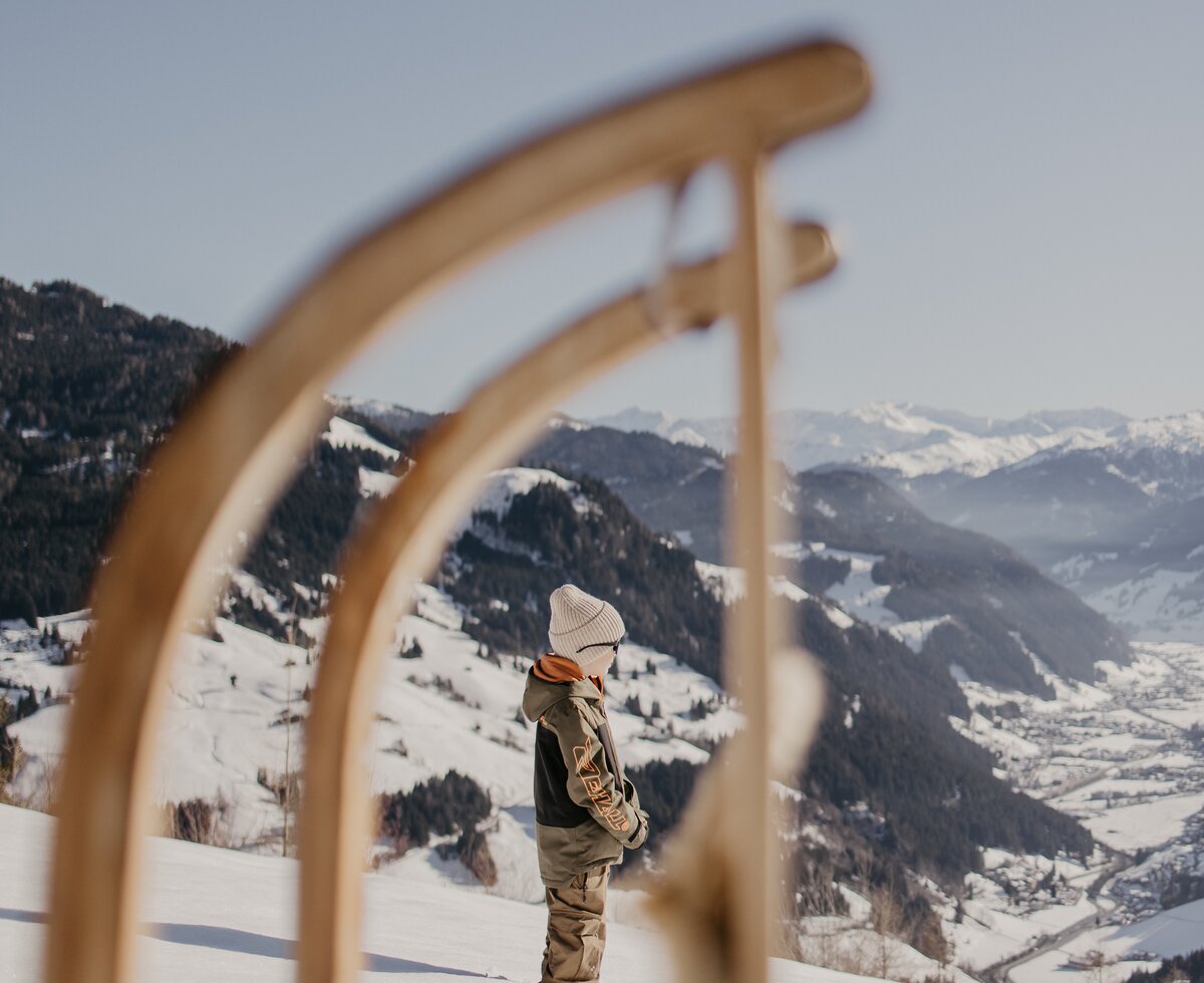 Ein Schlitten steht im Vordergrund und dahinter das Tal. | © Urlaub am Bauernhof im SalzburgerLand/ Love_Lens_Photograph