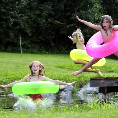 Die Kinder springen mit großen Schwimmreifen in den Badeteich, Süd-West-Steiermark, Steiermark | © Urlaub am Bauernhof Steiermark / Christa Strobl