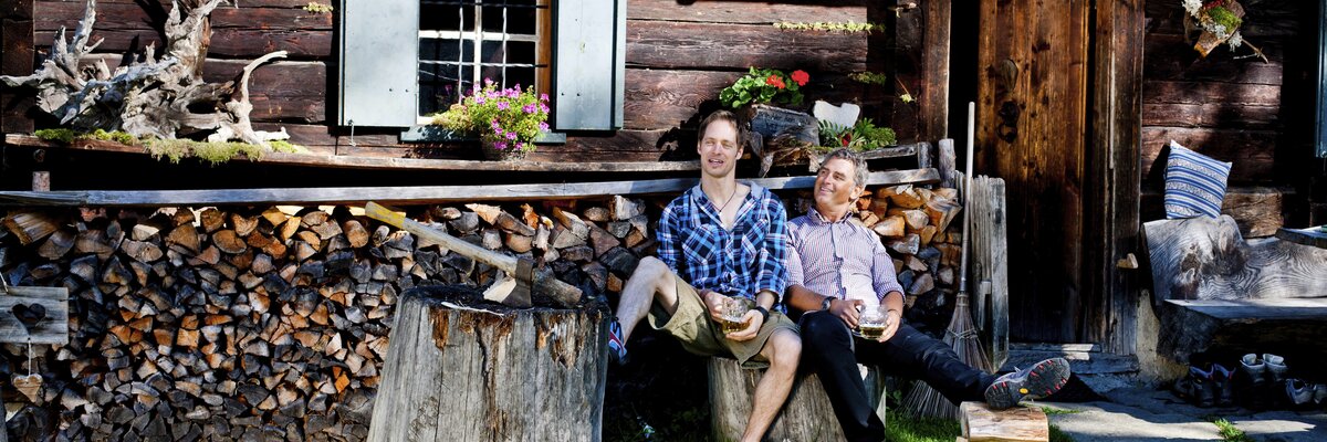 Zwei Männer sitzen nach dem Holzhacken vor der Hütte, Steiermark | © Urlaub am Bauernhof Steiermark / Kufferath