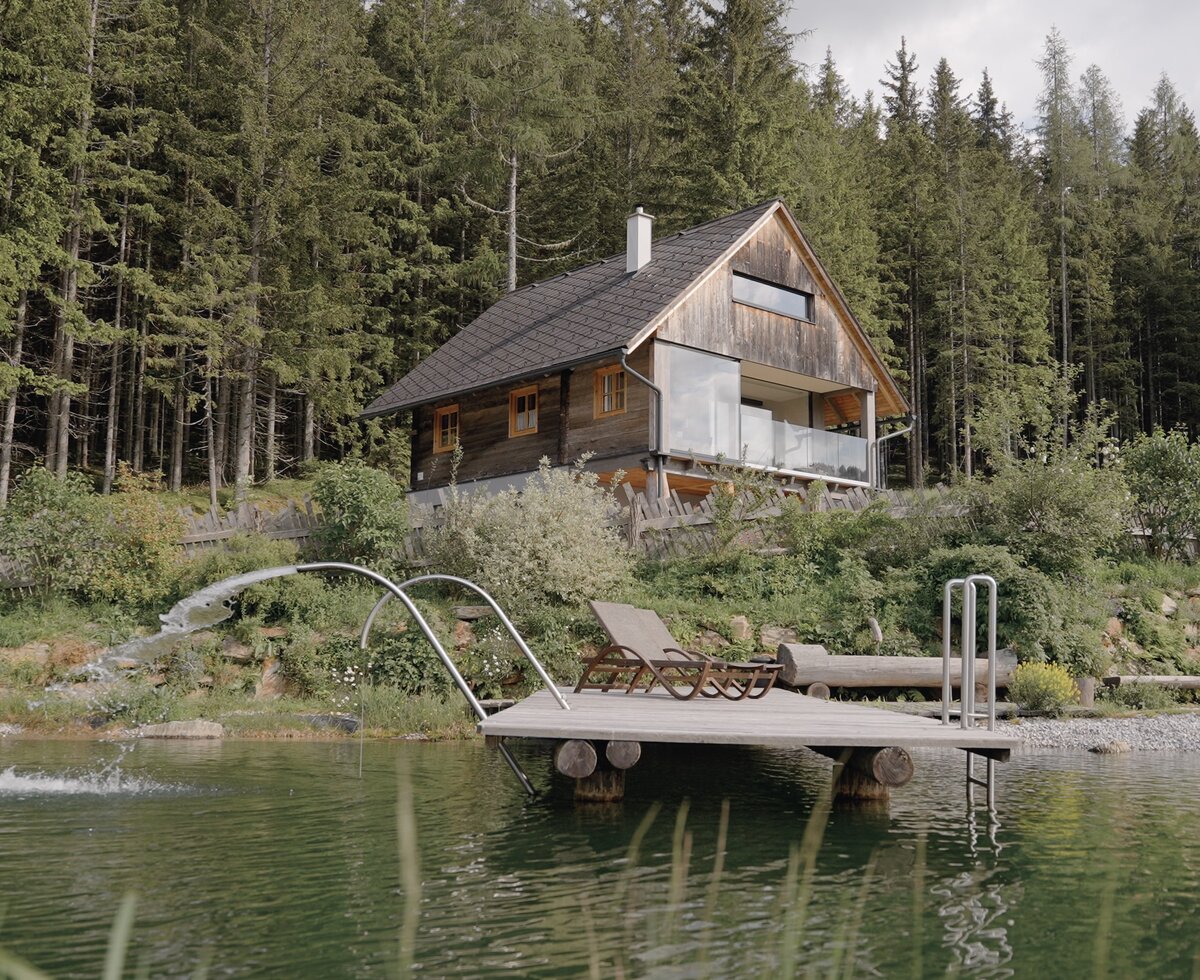 Ein Holzhaus am Waldrand mit einem davor liegenden Naturbadeteich | © Urlaub am Bauernhof Steiermark / Daniel Gollner
